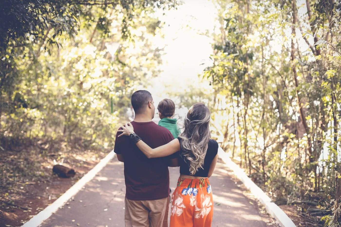 A family walking together along a sunlit park path