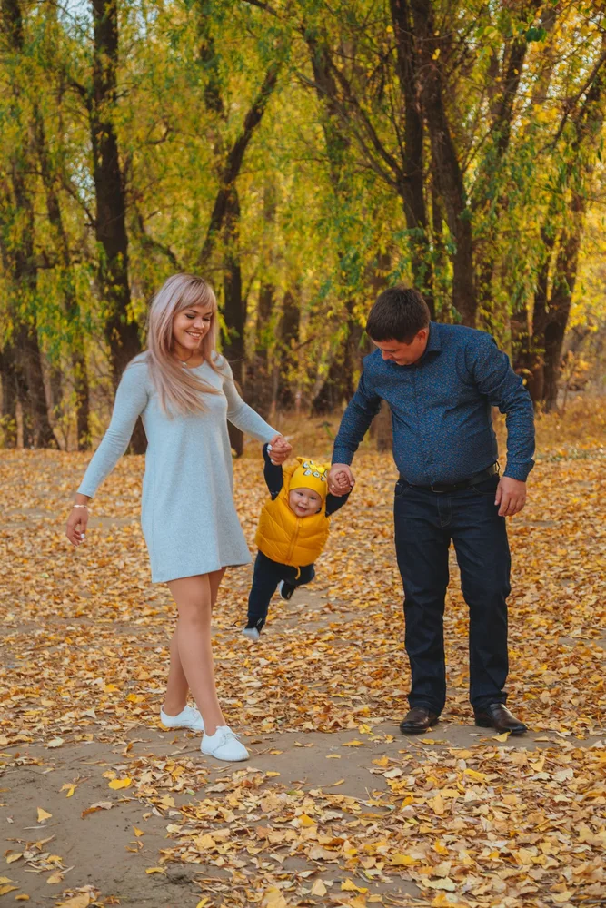 Parents walking with their child through an autumn park