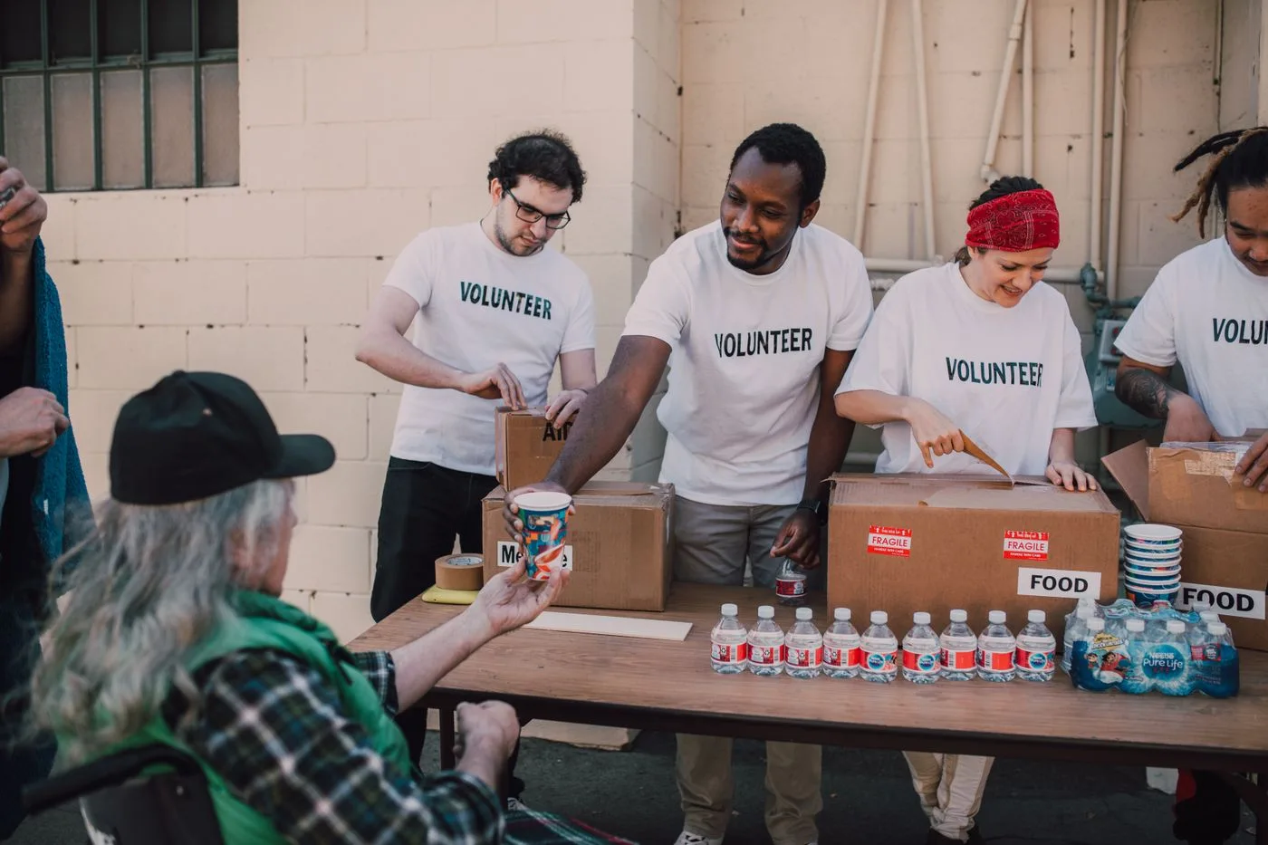 Volunteers welcoming people at an outdoor food distribution table