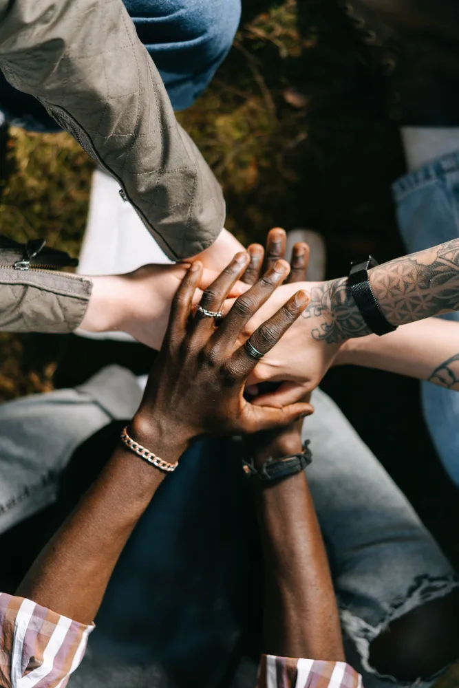 A group joining hands outdoors in a gesture of teamwork